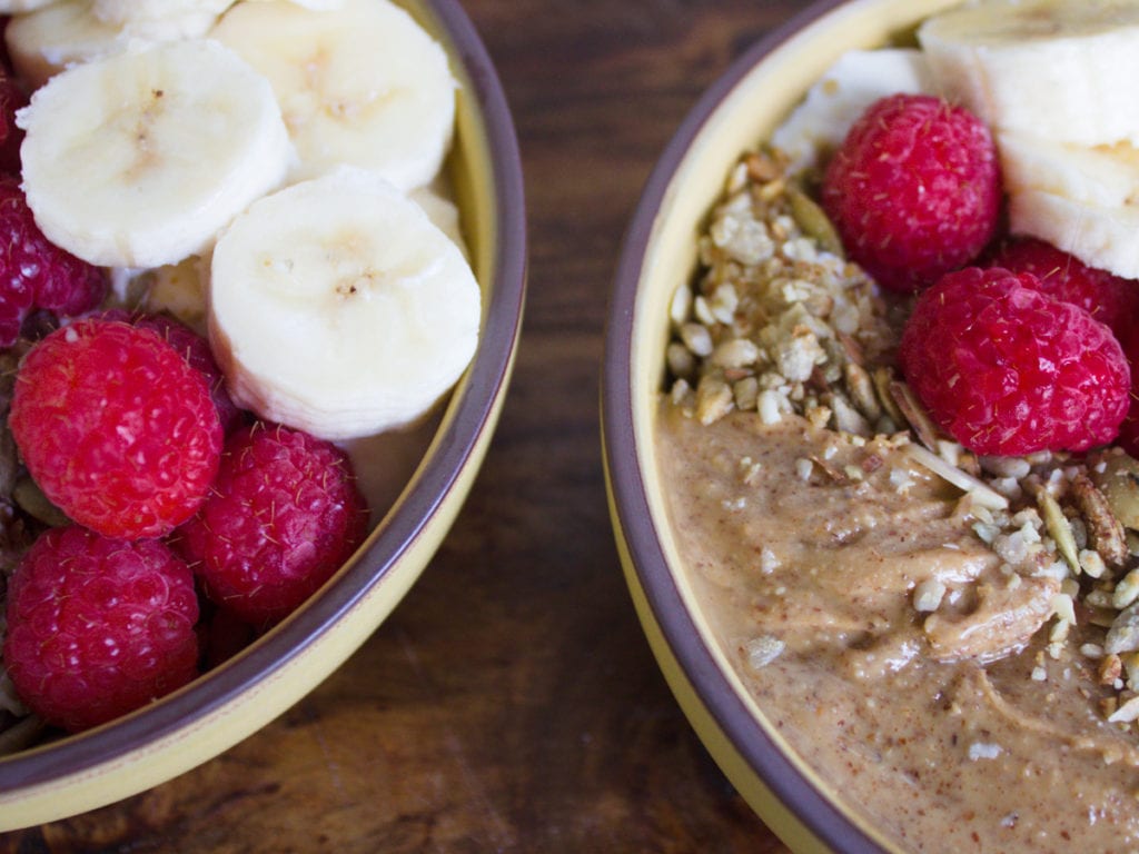 Almond butter breakfast Bowl with raspberries and bananas on table.