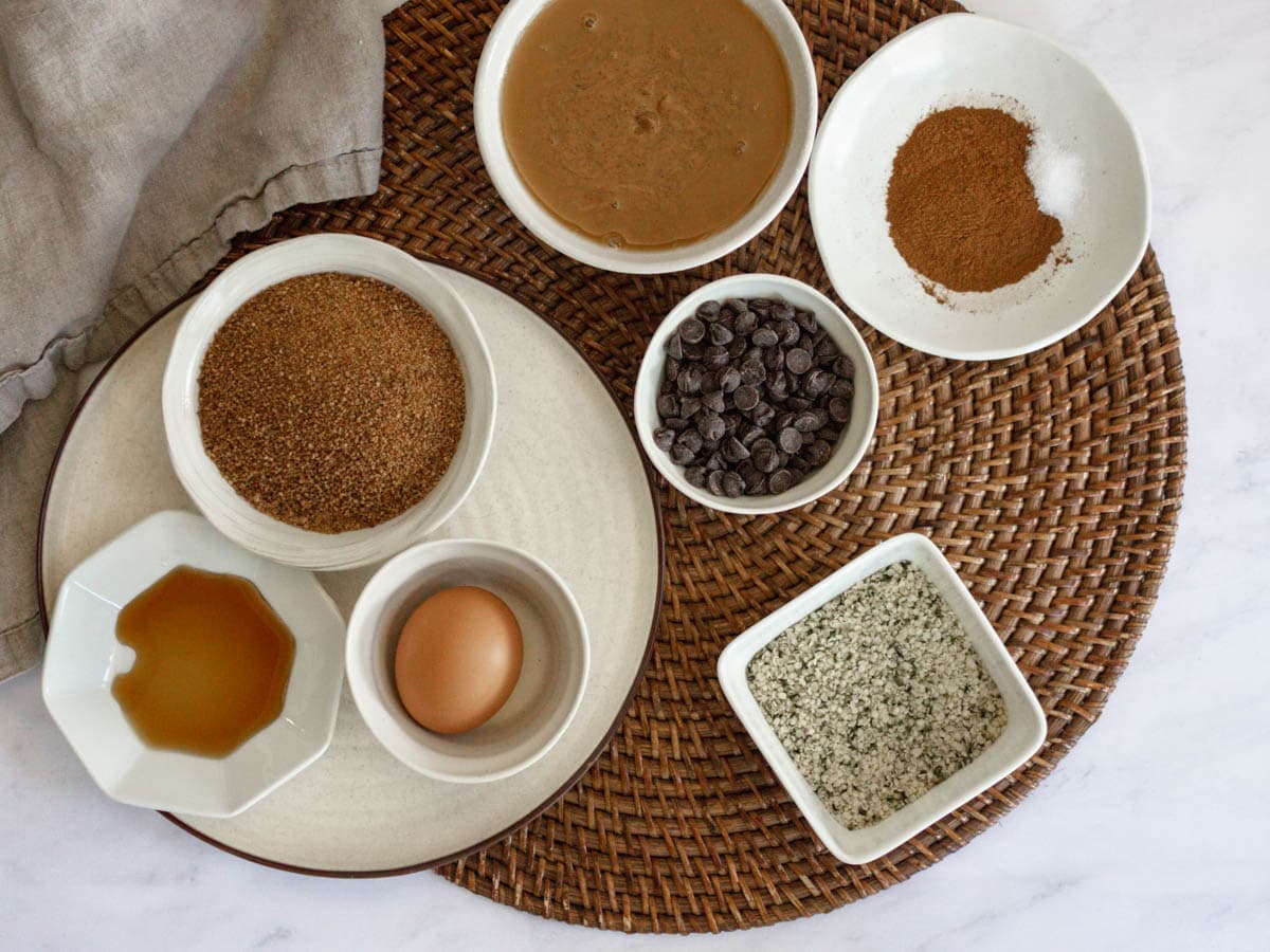 Overhead shot of ingredients needed to make hemp cookies. They are on top of a rattan placemat on a white countertop.