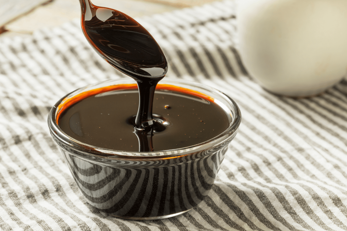 A spoonful of molasses pouring into a small glass bowl.