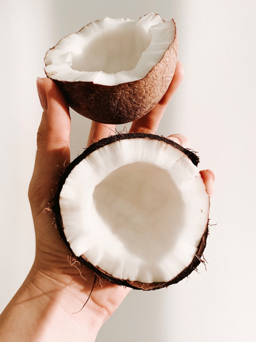 A hand holding a cracked open coconut.