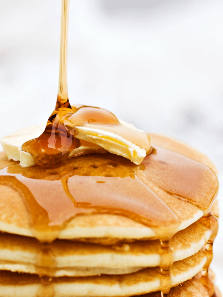 Maple syrup being poured on pancakes.