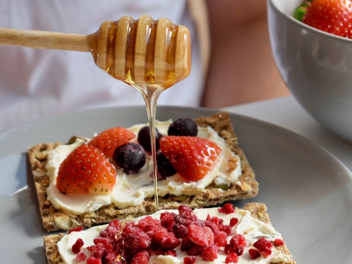 Honey drizzling on top of crackers with fruit. 