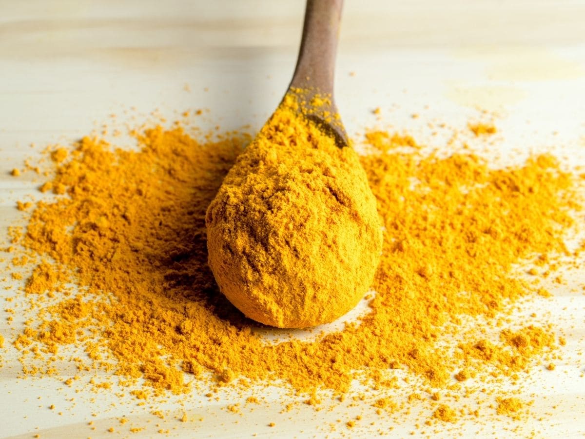 Saffron powder in a wooden spoon on a white counter top. 