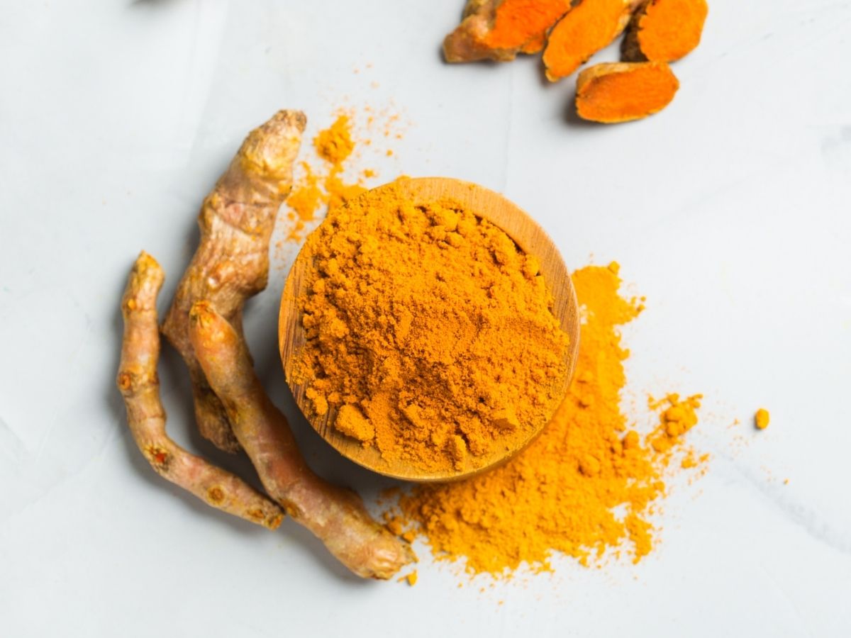Turmeric powder in a wooden bowl on a white counter. 