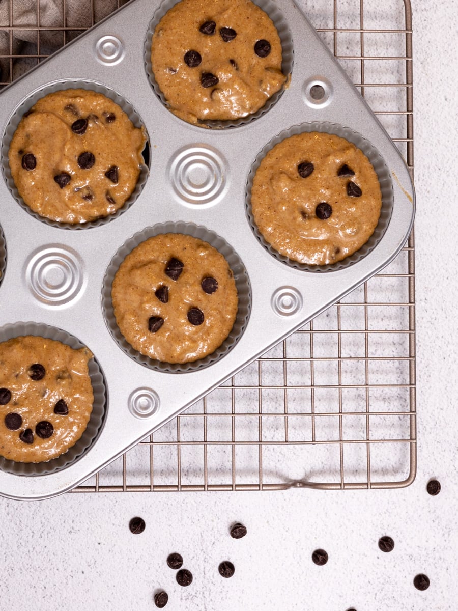 Muffin tin filled with protein muffin batter. Topped with chocolate chips. Ready to be baked. 