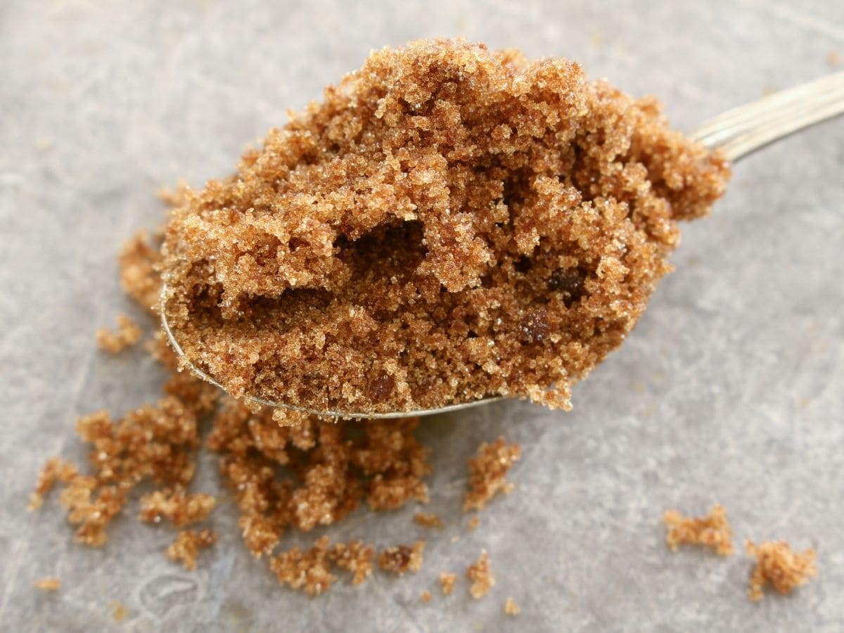 A spoonful of brown sugar on a grey countertop. 