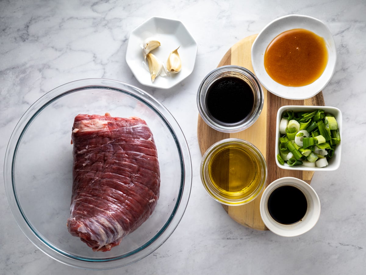 Ingredients needed for sous vide flank steak on a white countertop. 