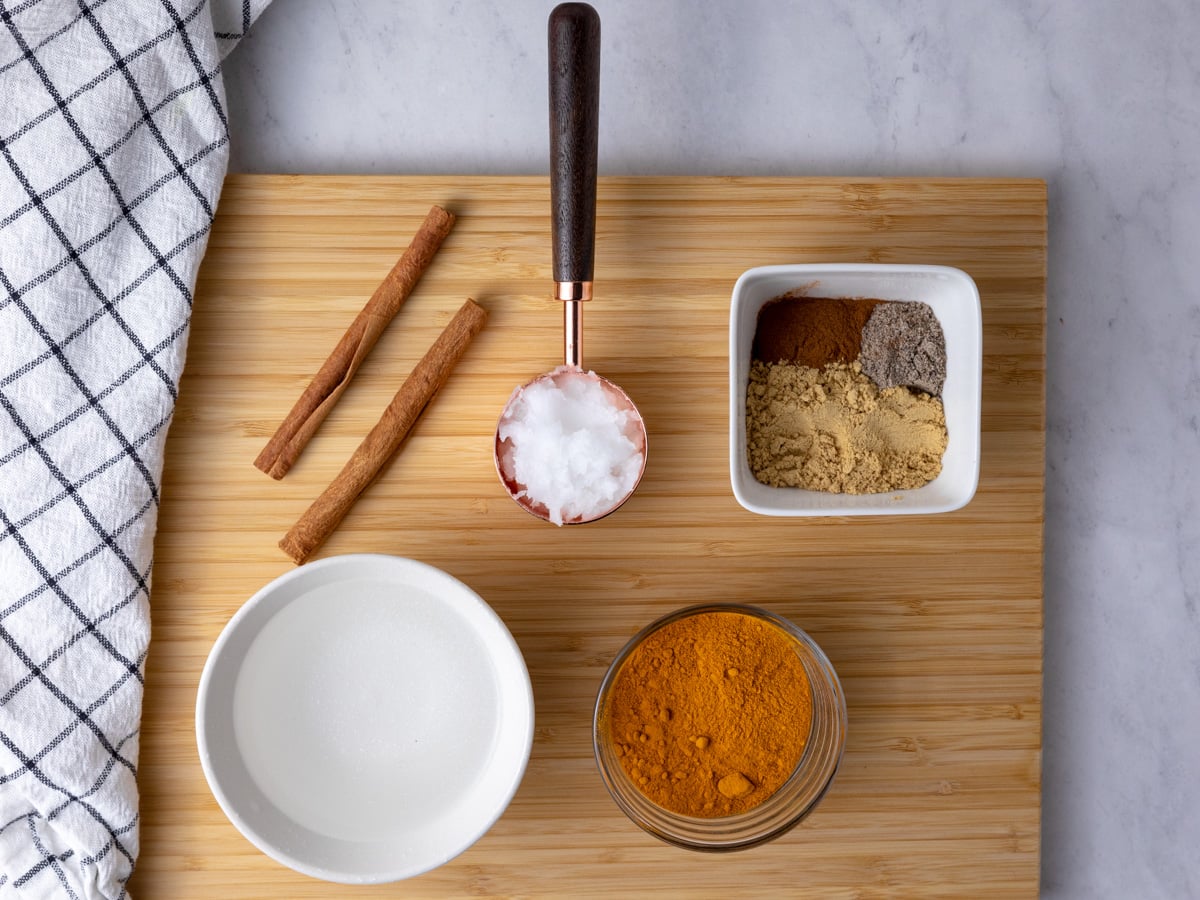 Ingredients needed to make turmeric paste on a wooden cutting board.