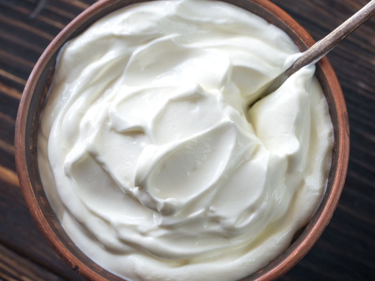 A bowl of greek yogurt on a wooden countertop.