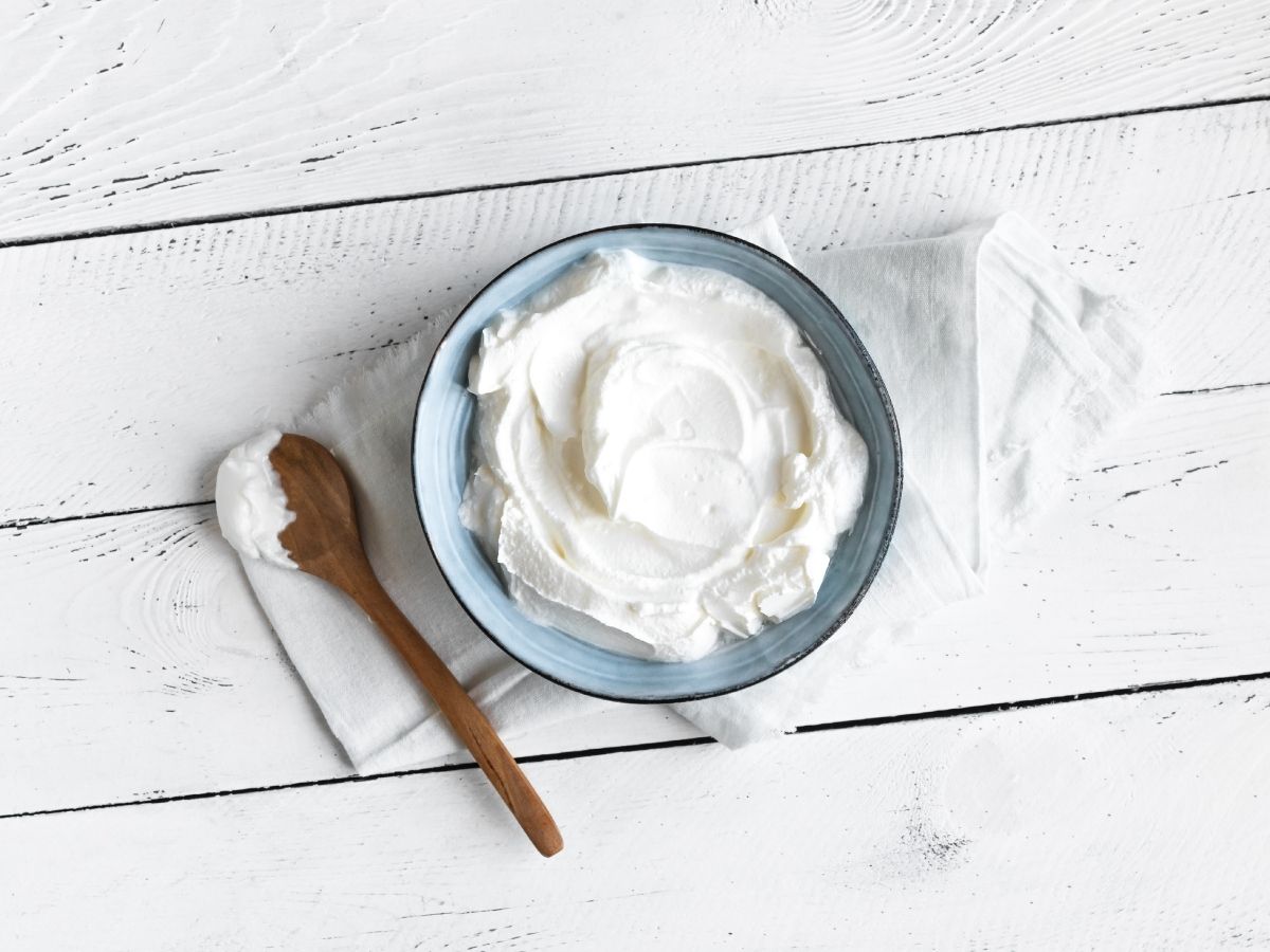 A bowl of greek yogurt on a white wooden countertop.