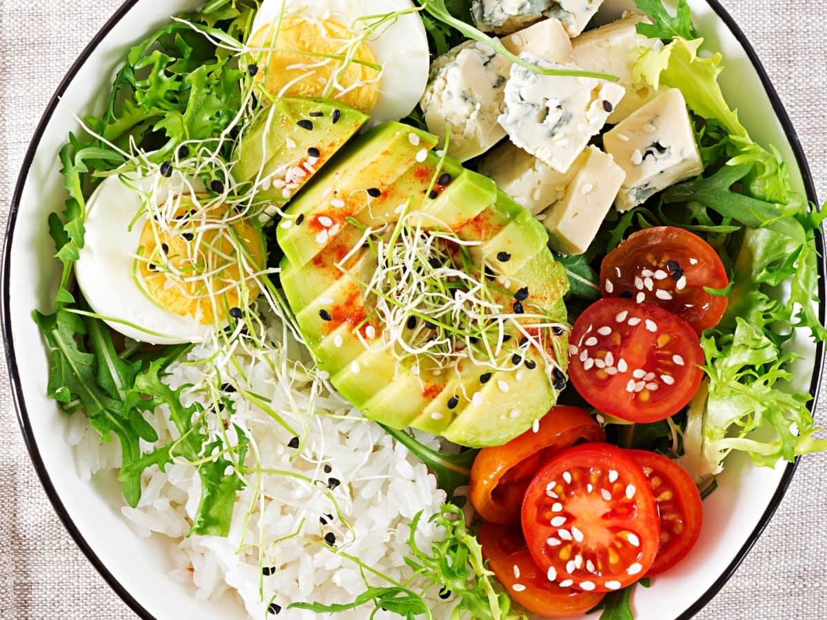 A healthy buddha bowl with avocado, eggs, rice, and vegetables. 