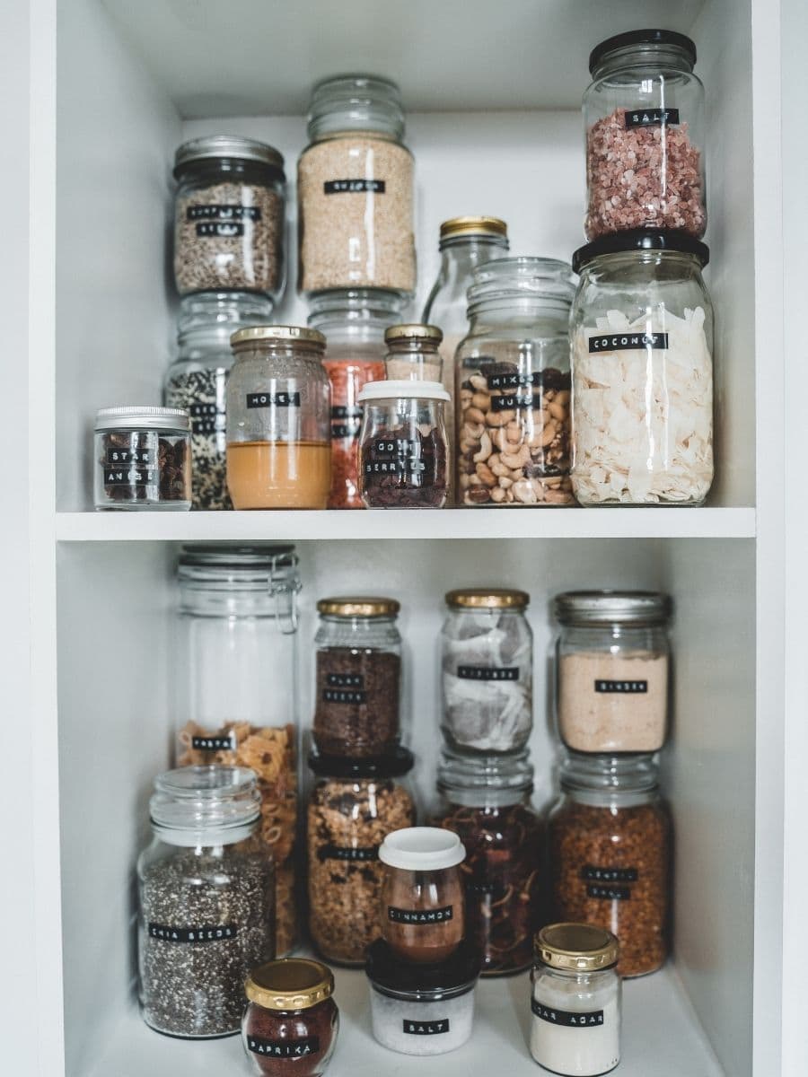 An organized pantry with flours, nuts and seeds in labeled glass jars. 