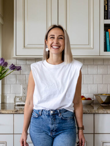 Girl smiling in the kitchen with purple tulips nearby.