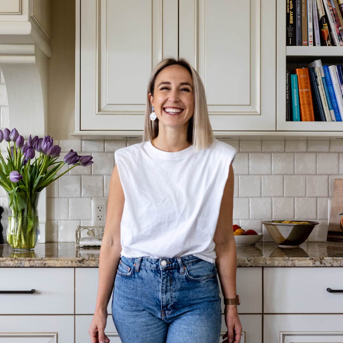 Girl smiling in the kitchen with purple tulips nearby.
