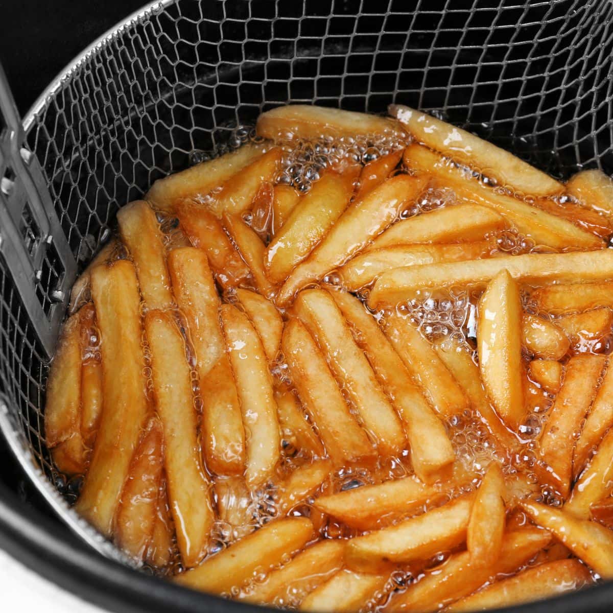 French fries submerged in a deep fryer. 