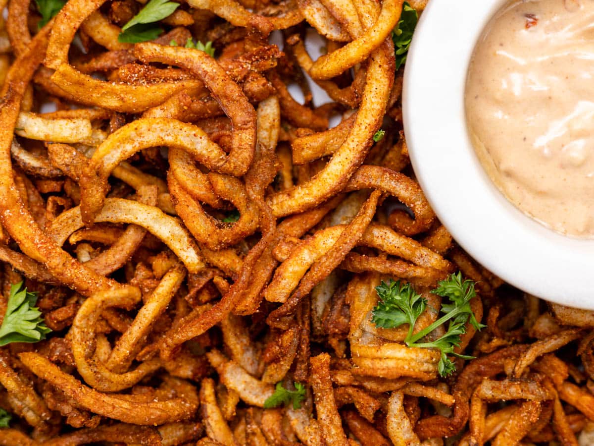 Up close shot of air fryer curly fries with parsley garnish. 