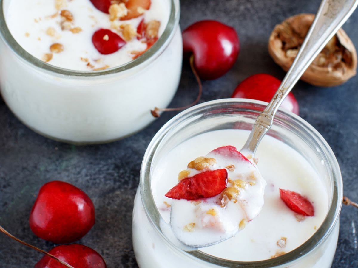 Kefir in a mason jar with cherries and granola. A second parfait sits behind it.