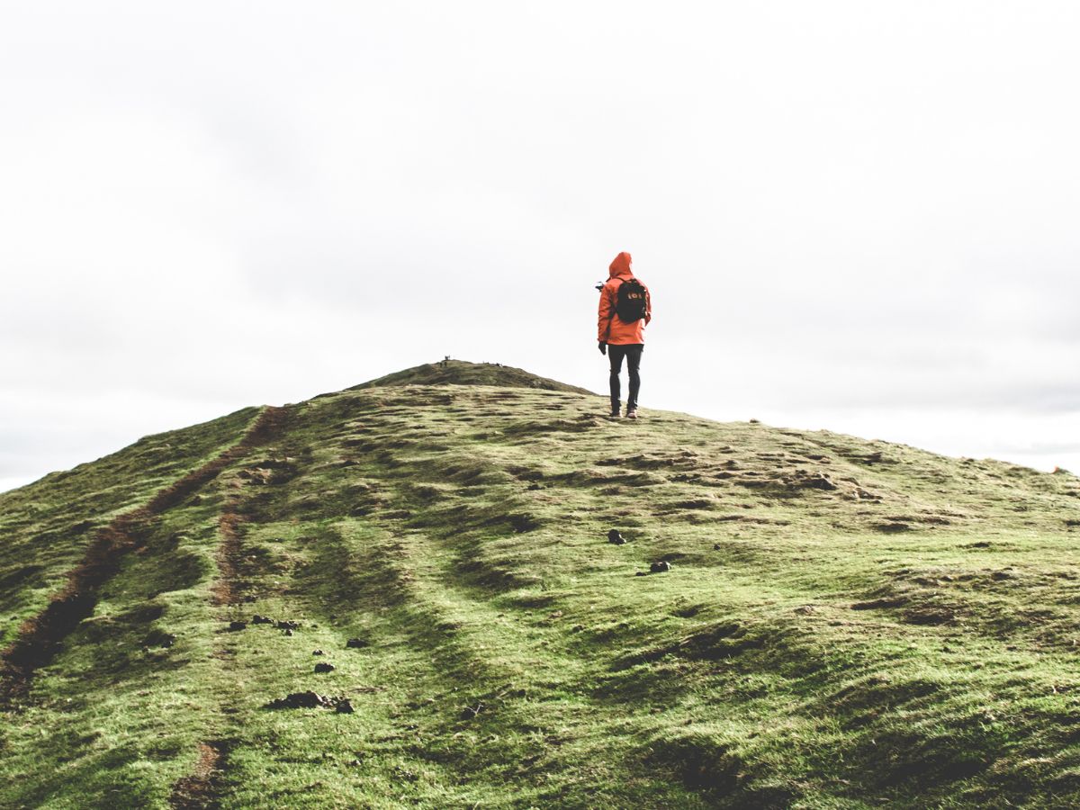 A person hiking on a green hill.