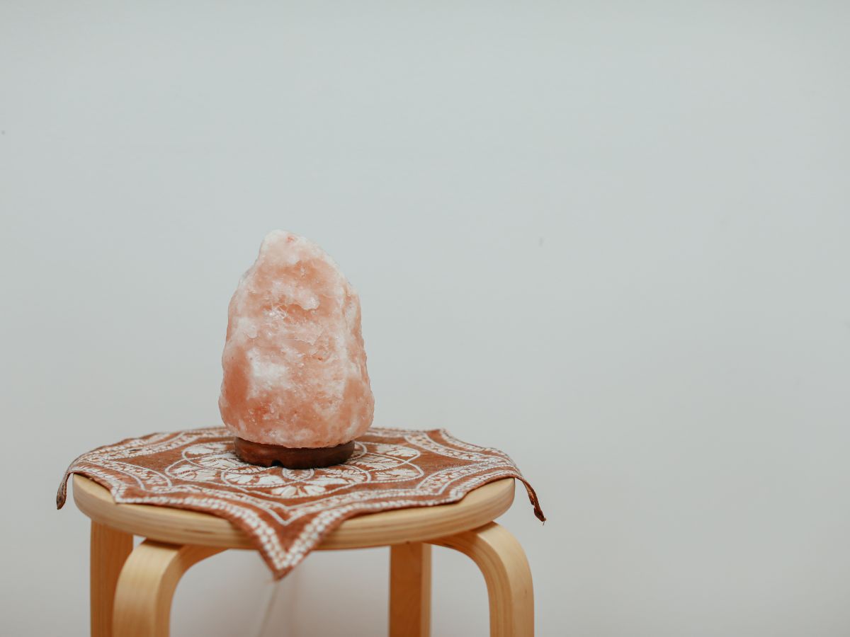 Himalayan salt lamp on a wooden table against a white wall.