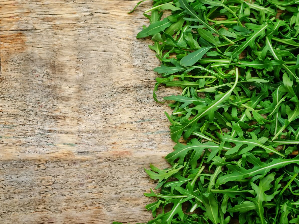 Up close shot of arugula on wooden cutting board.