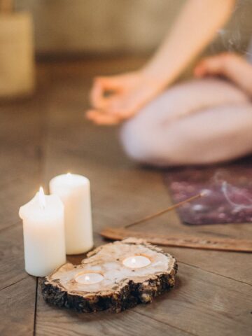 Woman meditating with candles nearby.