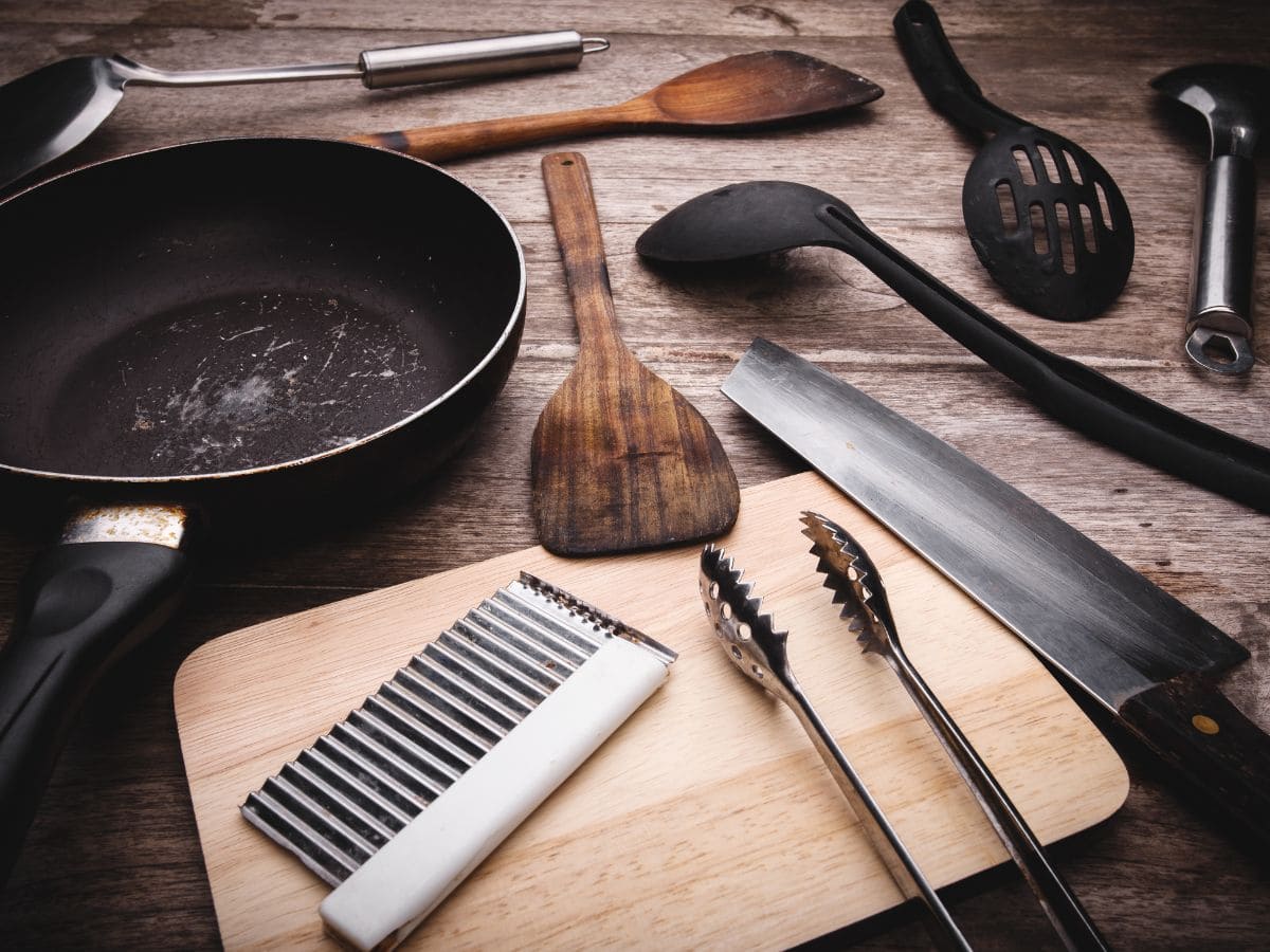 A variety of kitchen utensils on a wooden countertop.