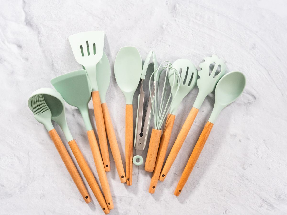 Pastel blue silicone kitchen utensils with wooden handles.