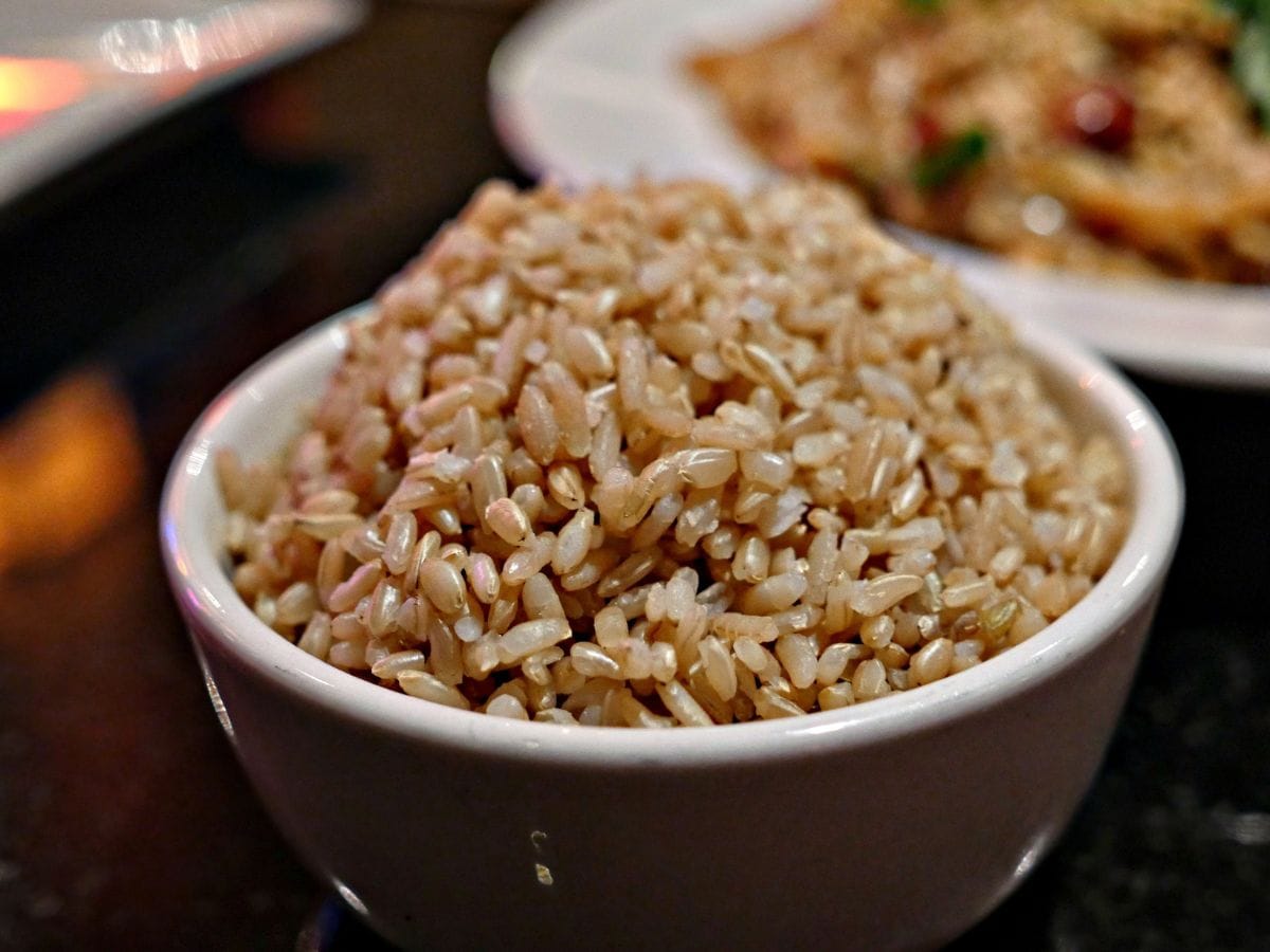 A bowl of brown rice on a wooden tabletop.