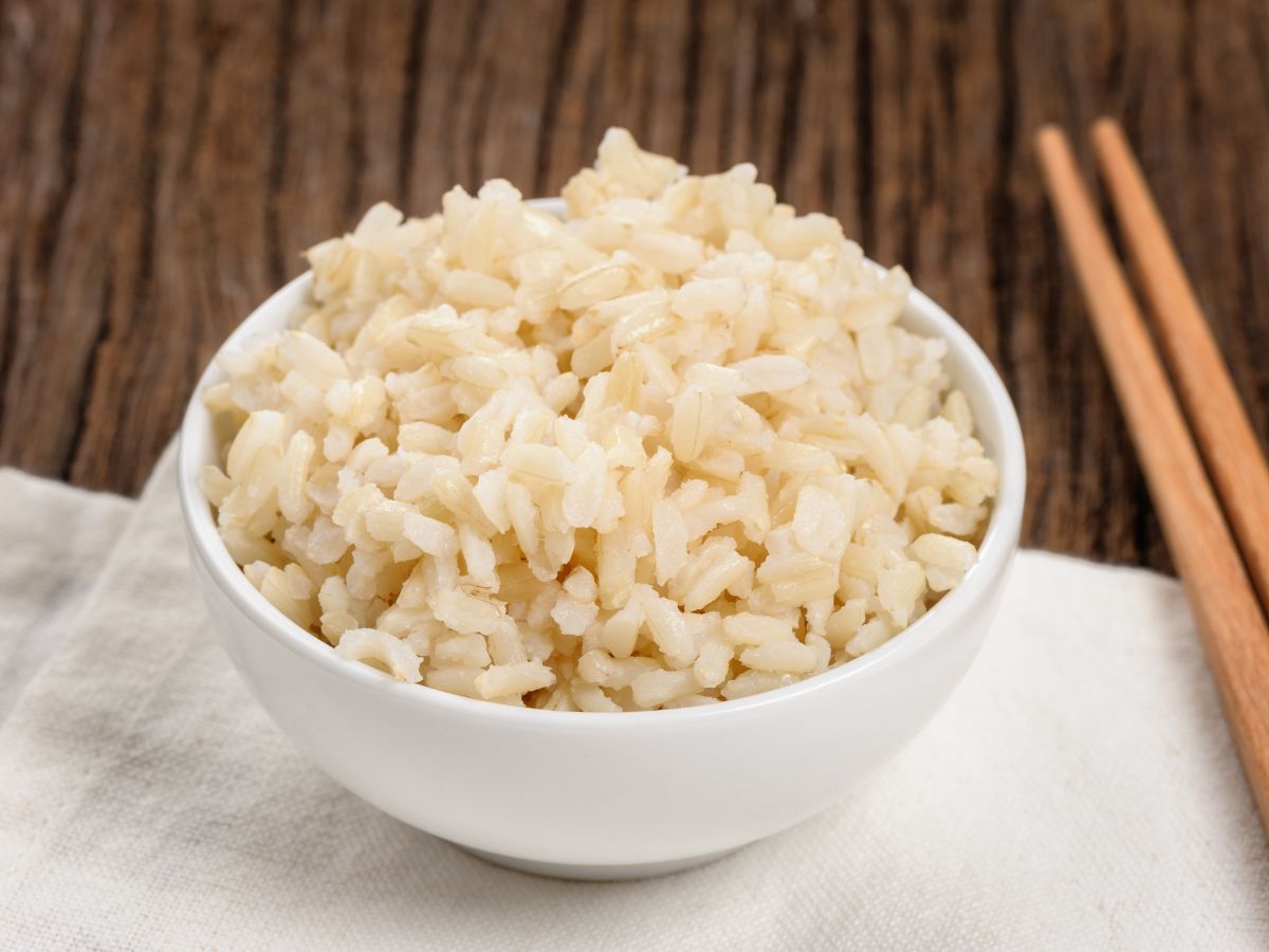A bowl of cooked rice on a wooden table.