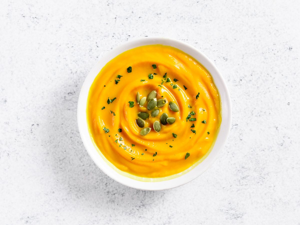 Pumpkin puree in a white bowl on a white countertop.