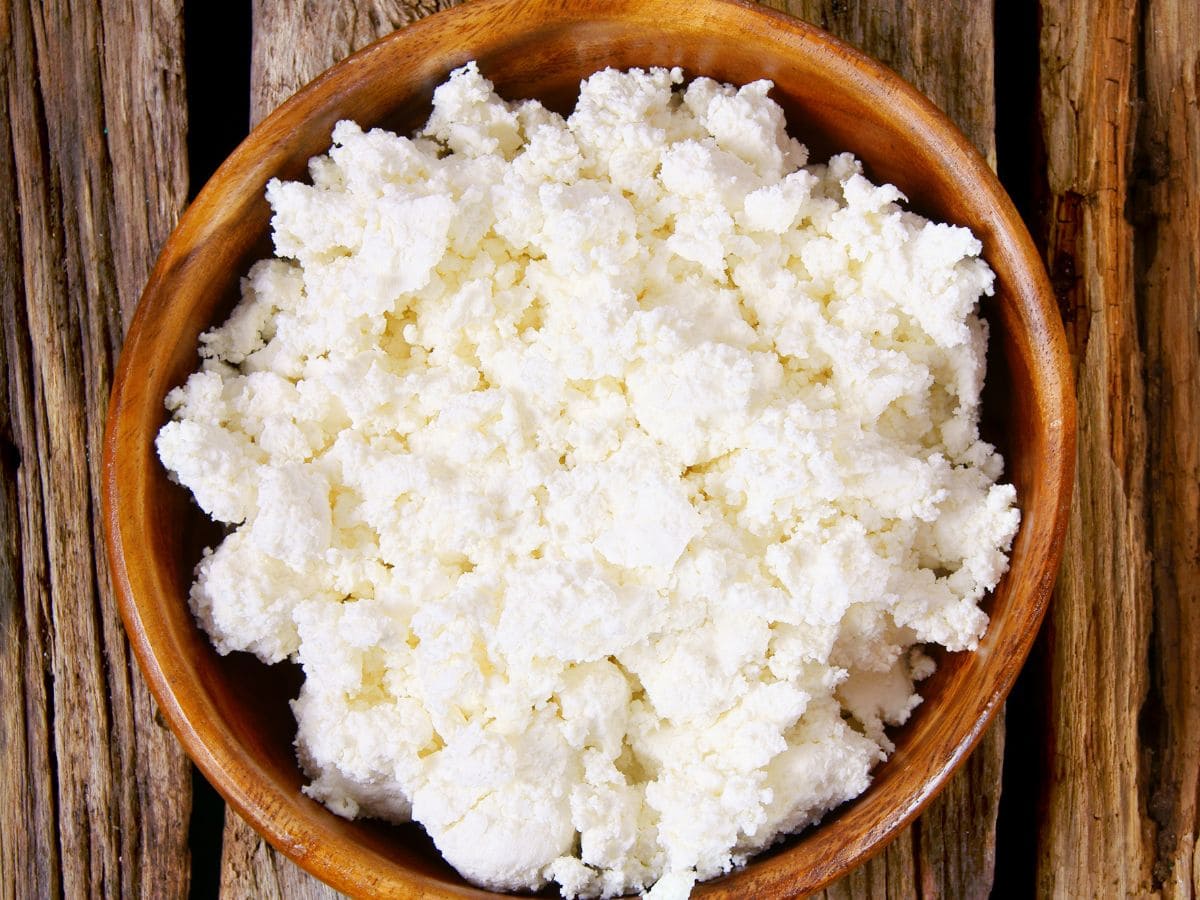 A wooden bowl filled with cottage cheese.