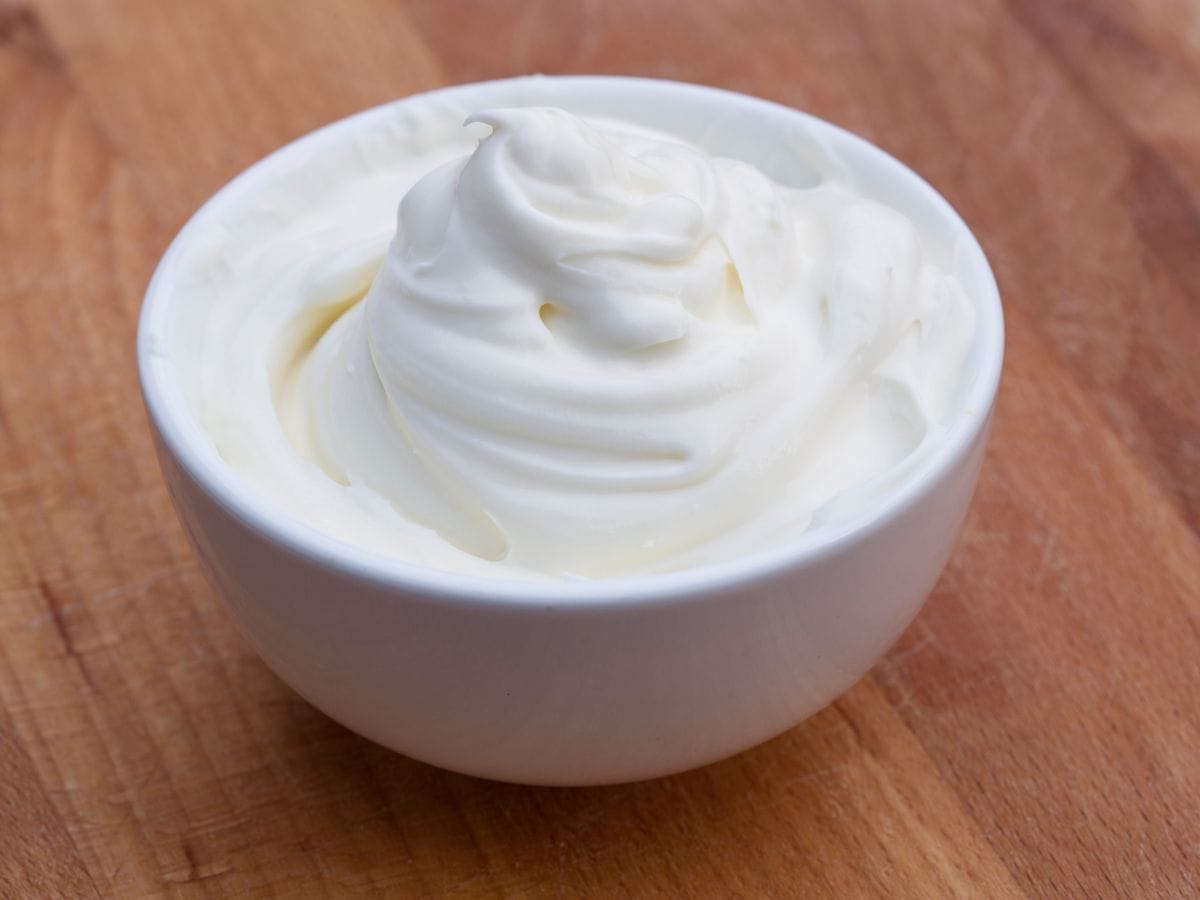 A bowl of sour cream on a wooden counter.